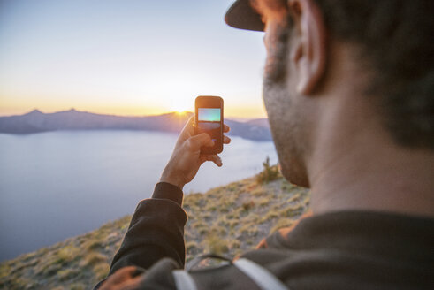 Wanderer beim Fotografieren mit dem Handy im Crater Lake National Park bei Sonnenuntergang - CAVF34657