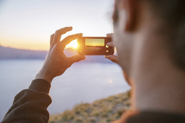 Close-up of hiker photographing at Crater Lake National park during sunset - CAVF34658