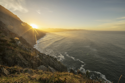 Scenic view of silhouette cliff by sea against sky stock photo