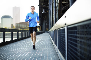 Full length of man jogging on bridge in city - CAVF34667