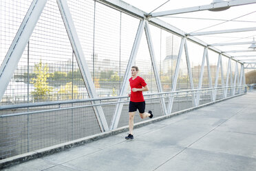 Man running while exercising on bridge in city - CAVF34675