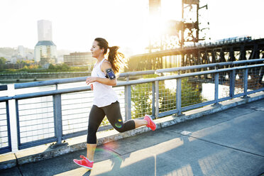 Frau in voller Länge beim Joggen auf der Brücke - CAVF34677