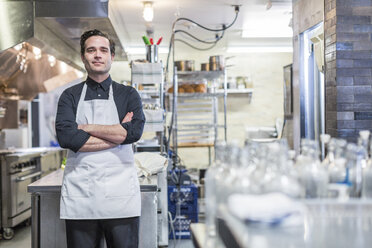 Porträt eines selbstbewussten männlichen Kochs mit verschränkten Armen in einer Restaurantküche - CAVF34689