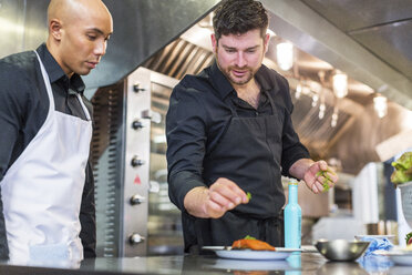 Männliche Köche beim Garnieren von Speisen an der Küchentheke eines Restaurants - CAVF34698