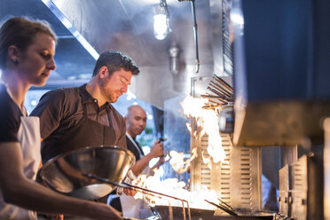 Köche bereiten Essen in Flammen in der Restaurantküche zu - CAVF34705