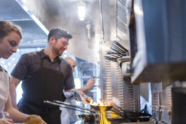 Köche bei der Zubereitung von Speisen in Flammen in der Küche eines Restaurants - CAVF34706