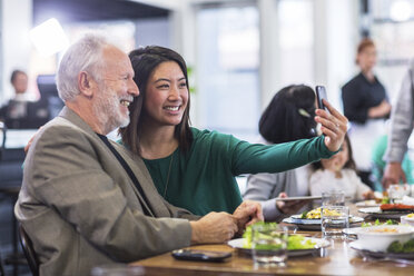 Frau macht Selfie mit älterem Mann im Restaurant - CAVF34723