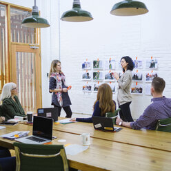 Businesswoman explaining to colleagues in meeting at board room - CAVF34783