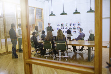 Business people in meeting at board room seen through glass - CAVF34786