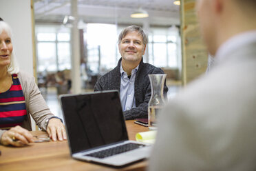 Businessman discussing with colleagues at desk in office - CAVF34820