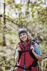 Portrait of happy female hiker standing in forest - CAVF34856