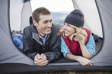 Glückliches Paar liegt im Zelt auf dem Campingplatz - CAVF34862