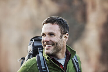 Happy man looking away while hiking on field - CAVF34870