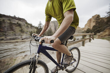 Tiefschnitt eines Mannes beim Fahrradfahren auf der Promenade am Fluss - CAVF34875