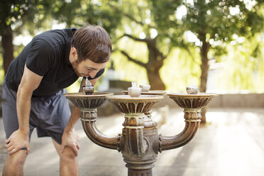 Mann trinkt Wasser aus einem Springbrunnen - CAVF34921