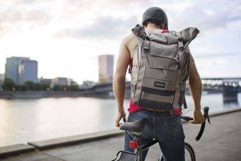 Mann trägt Rucksack beim Fahrradfahren auf der Straße - CAVF34922