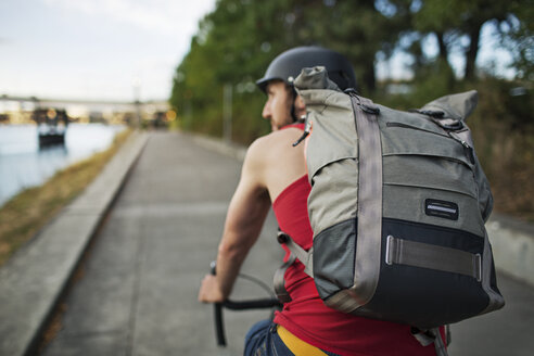 Mann trägt Rucksack beim Fahrradfahren auf der Straße - CAVF34924