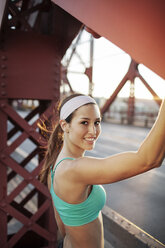 Porträt einer glücklichen jungen Frau beim Sport auf einer Brücke - CAVF34951