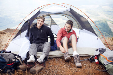 Glückliches Paar sitzt im Zelt auf einem Berg - CAVF34967