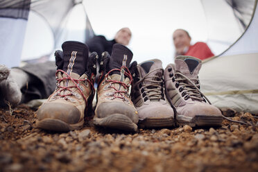 Nahaufnahme von schmutzigen Schuhen mit entspannenden Wanderern im Hintergrund - CAVF34969