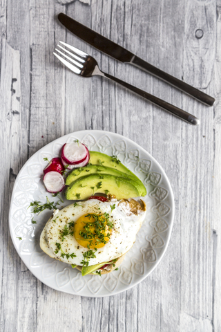 Toast with with fried egg, avocado, red radish, tomato and cress stock photo