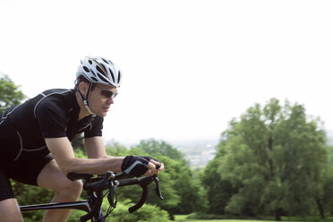 Side view of determined cyclist sitting on bicycle against clear sky - CAVF35042