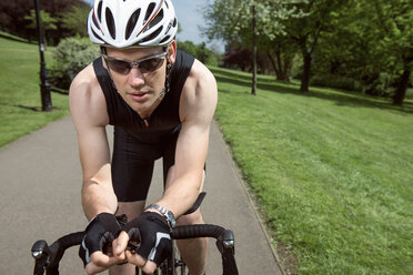Porträt eines selbstbewussten Radfahrers, der auf einem Fahrrad inmitten eines Feldes sitzt - CAVF35043