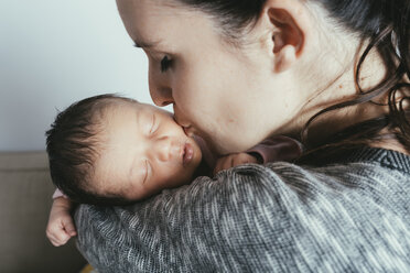 Close-up of woman kissing baby girl at home - CAVF35067