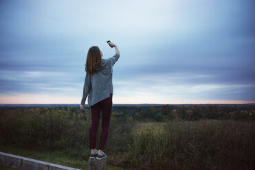 Rear view of teenage girl taking selfie at dusk - CAVF35081