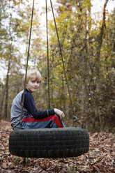 Portrait of boy sitting on tire swing - CAVF35090