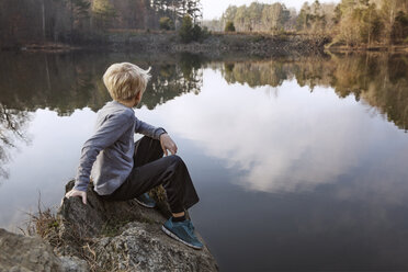 Junge sitzt auf einem Felsen am See - CAVF35106