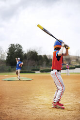 Side view of boy playing baseball with coach on field against sky - CAVF35121