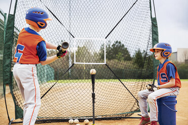 Junge sieht seinen Freund an, der auf einem Feld Baseball spielt - CAVF35122