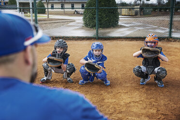 Rear view of coach training baseball catchers on field - CAVF35126