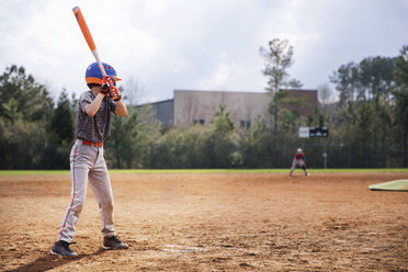 Side view of boy swinging baseball bat on field - CAVF35131