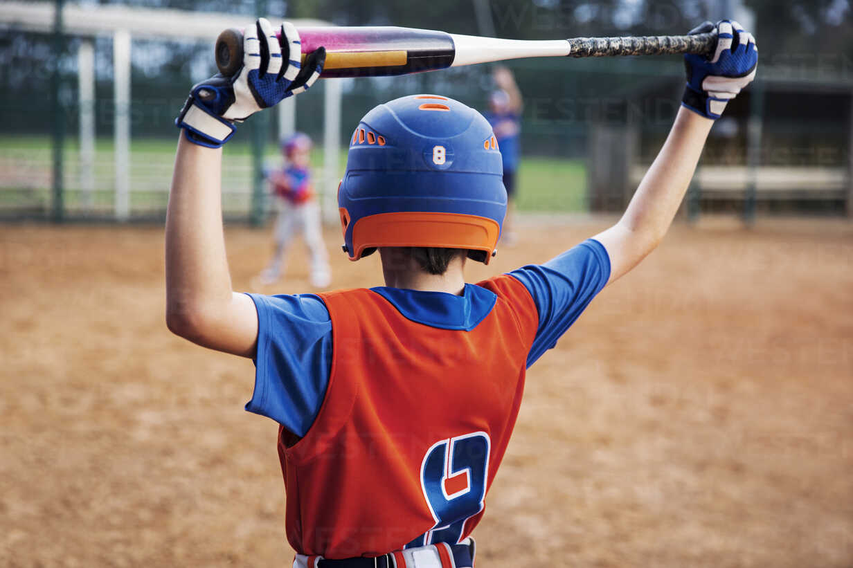 Rear view of boy holding baseball bat on field stock photo