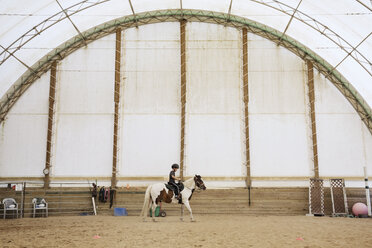 Seitenansicht eines Jungen auf einem Pferd in einer Ranch - CAVF35143