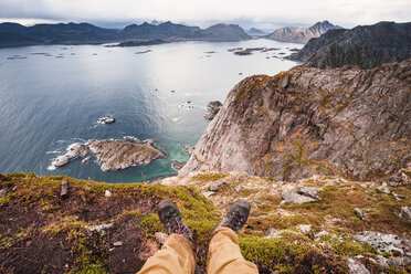 Norwegen, Lofoten, Henningsvaer, Wanderer sitzt auf Aussichtspunkt - WVF00990