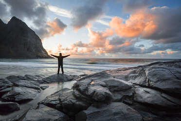 Norway, Lofoten Islands, man with raised arms at Kvalvika Beach in the evening - WVF01022