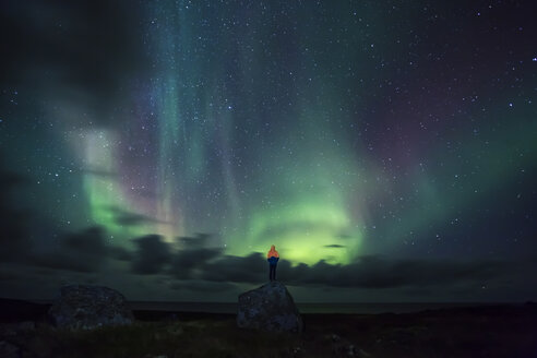 Norwegen, Lofoten-Inseln, Eggum, Mann steht auf einem Felsen und beobachtet Nordlicht - WVF01024
