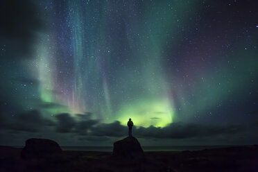 Norway, Lofoten Islands, Eggum, man standing on rock and watching northern lights - WVF01025