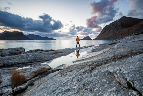 Norway, Lofoten Islands, Haukland Beach, hiker standing on rock stock photo