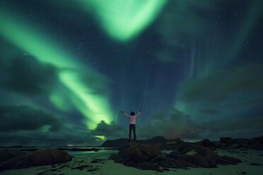 Norway, Lofoten Islands, Eggum, northern lights, young man with raised arms - WVF01044
