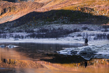 Norwegen, Lofoten-Inseln, Mann steht am Wasser in Winterlandschaft - WVF01054