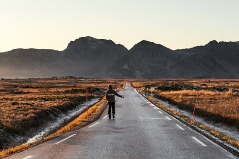 Norwegen, Lofoten, Rückenansicht eines Anhalters an einer leeren Landstraße - WVF01071