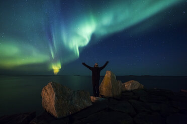Norway, Lofoten Islands, Eggum, back view of man standing on rock admiring Northern lights - WVF01082