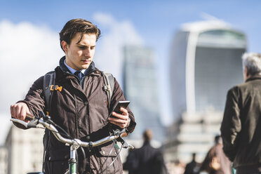 UK, London, Geschäftsmann mit Fahrrad schaut auf Handy - WPEF00159