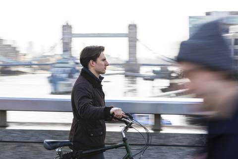 UK, London, Geschäftsmann schiebt Fahrrad in der Stadt, lizenzfreies Stockfoto