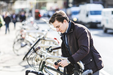 Businessman locking bicycle in the city - WPEF00163