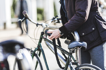 Geschäftsmann schließt Fahrrad in der Stadt ab, Teilansicht - WPEF00164